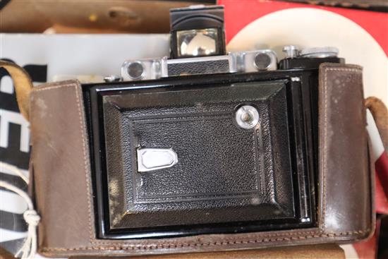 A Leitz black Leica R4 body in presentation box, a Zeiss Ikon Super Ikonta folding bellows camera and sundry accessories